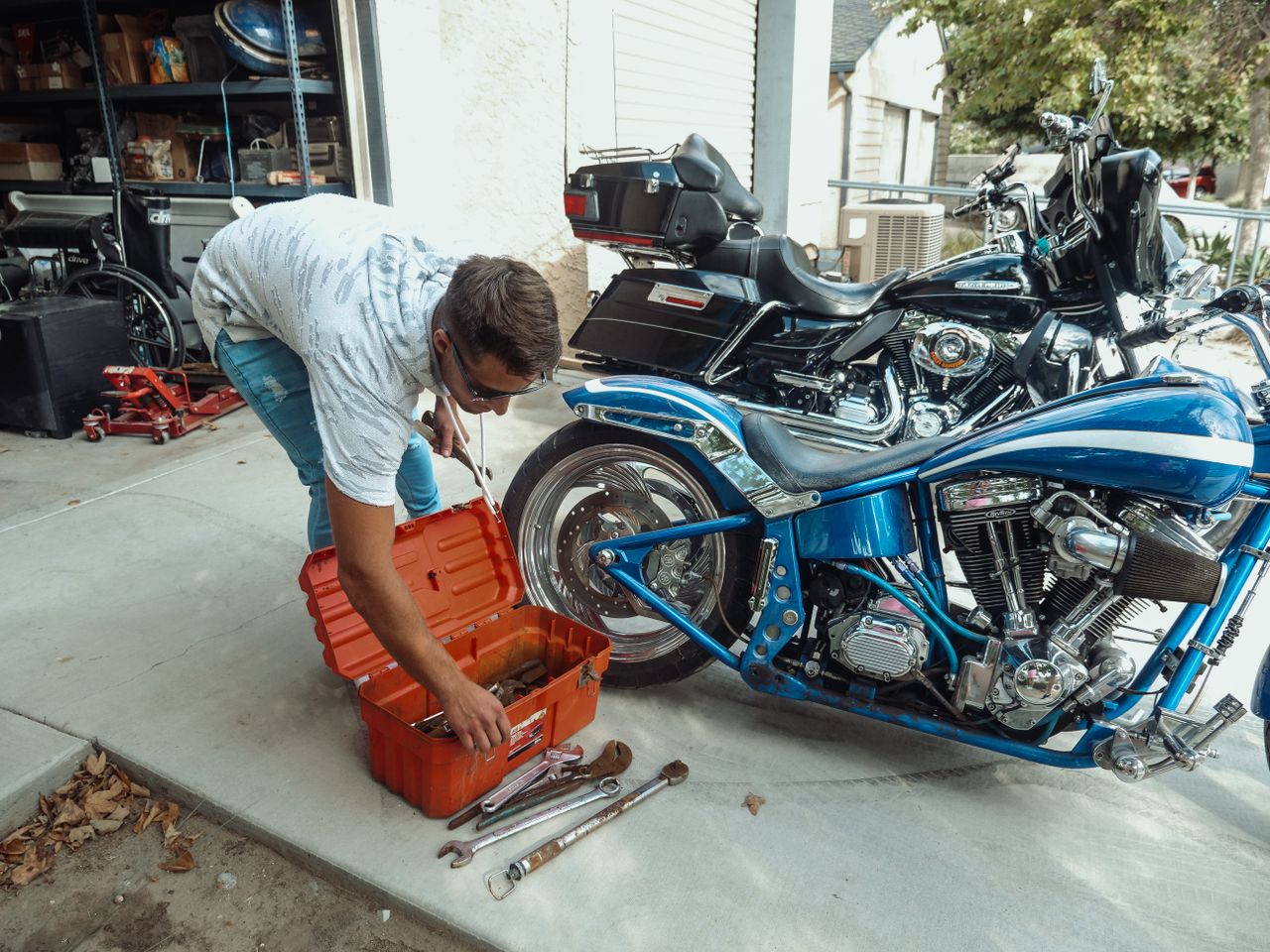 Man working on his motorcycle in his driveway Man working on his motorcycle in his driveway