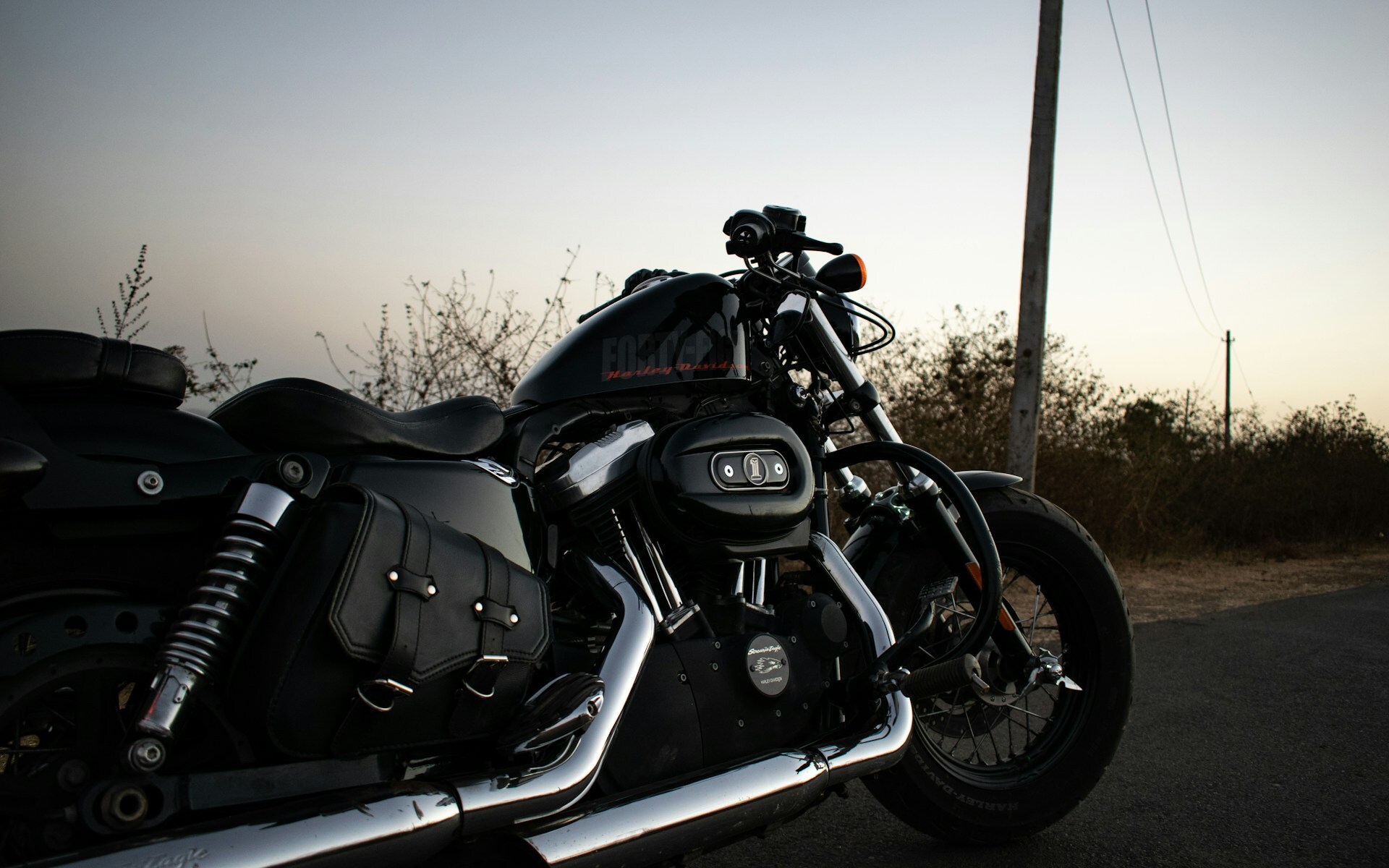 A Harley Davidson motorcycle parked on the side of a road during sunset
